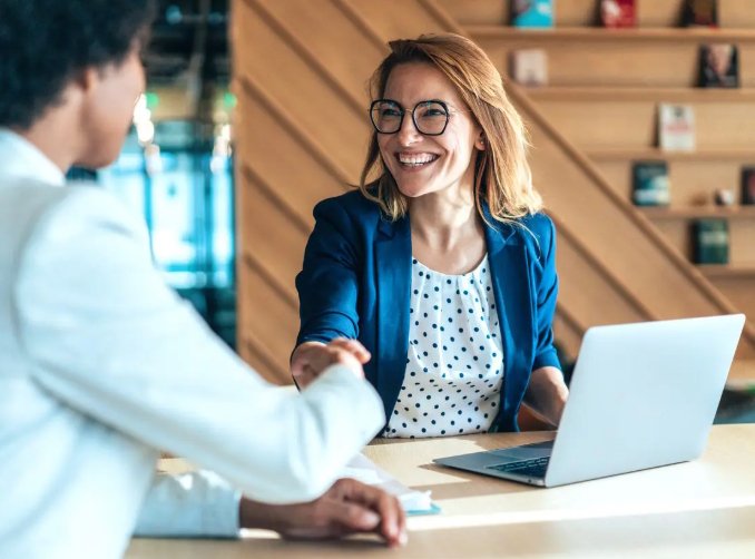 Real estate agent discussing transparent fees with client while reviewing property details on a laptop in France