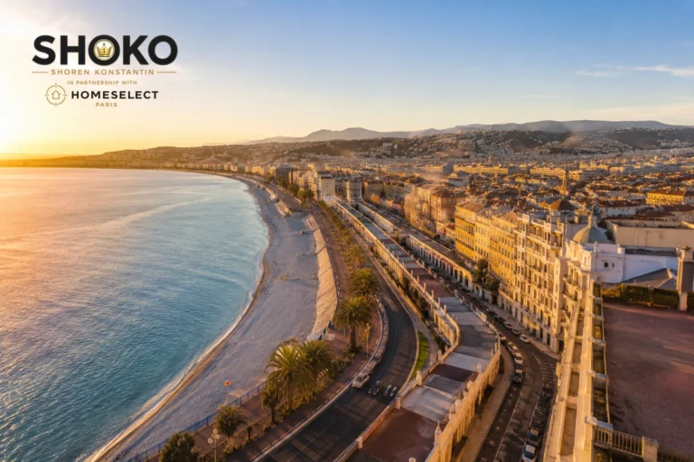 Panoramic view of Nice's Promenade des Anglais curving along the azure Mediterranean coastline with classic Belle Époque buildings lining the seafront