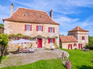 SHOKO standing before a honey-stone Périgord country house in the Dordogne